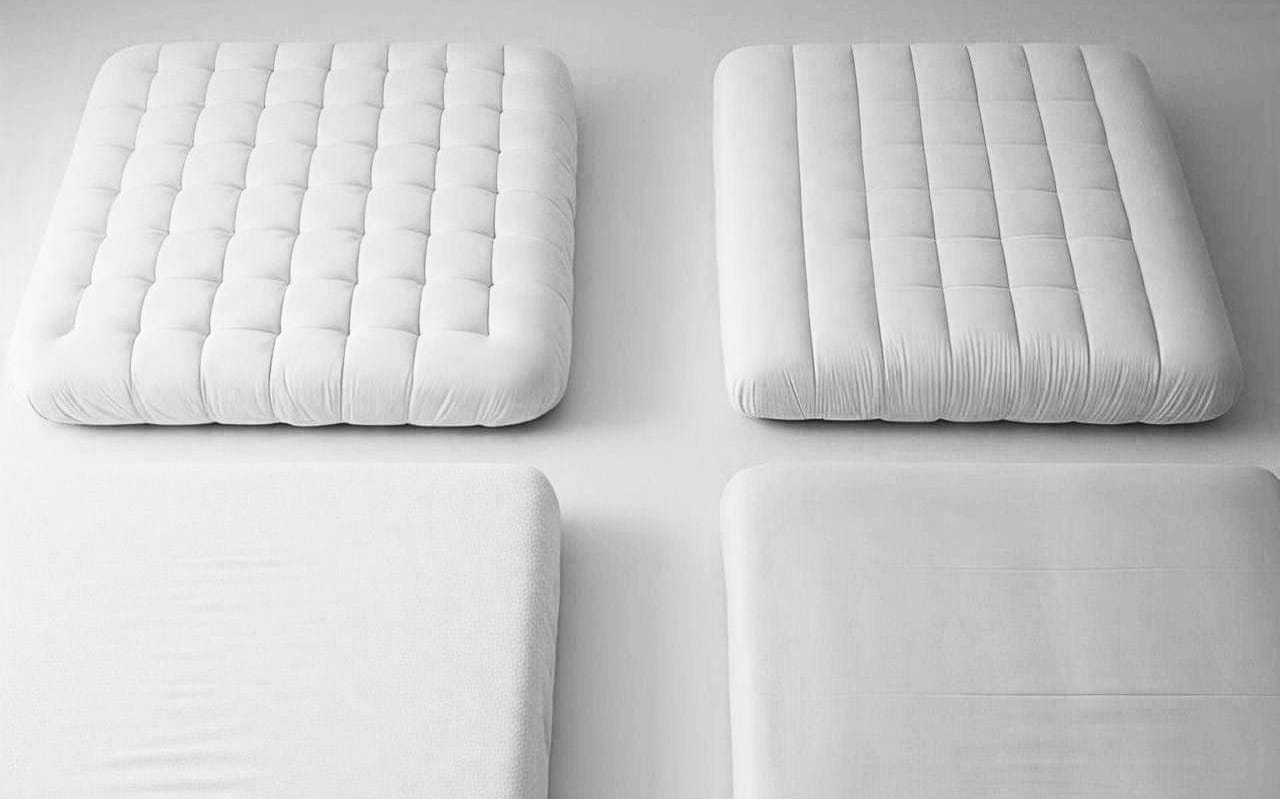 Four white mattress pads displayed side by side, showcasing different levels of thickness and quilting patterns. These cooling mattress pads offer comfort and temperature regulation for a better sleep experience.